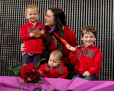 Christine Girard, accompagnée de ses trois enfants, sur le podium lors de la cérémonie du 3 décembre 2018 pour lui remettre la médaille d'or et la médaille de bronze en haltérophilie pour les Jeux Olympiques de Londres 2012 et Pékin 2008.